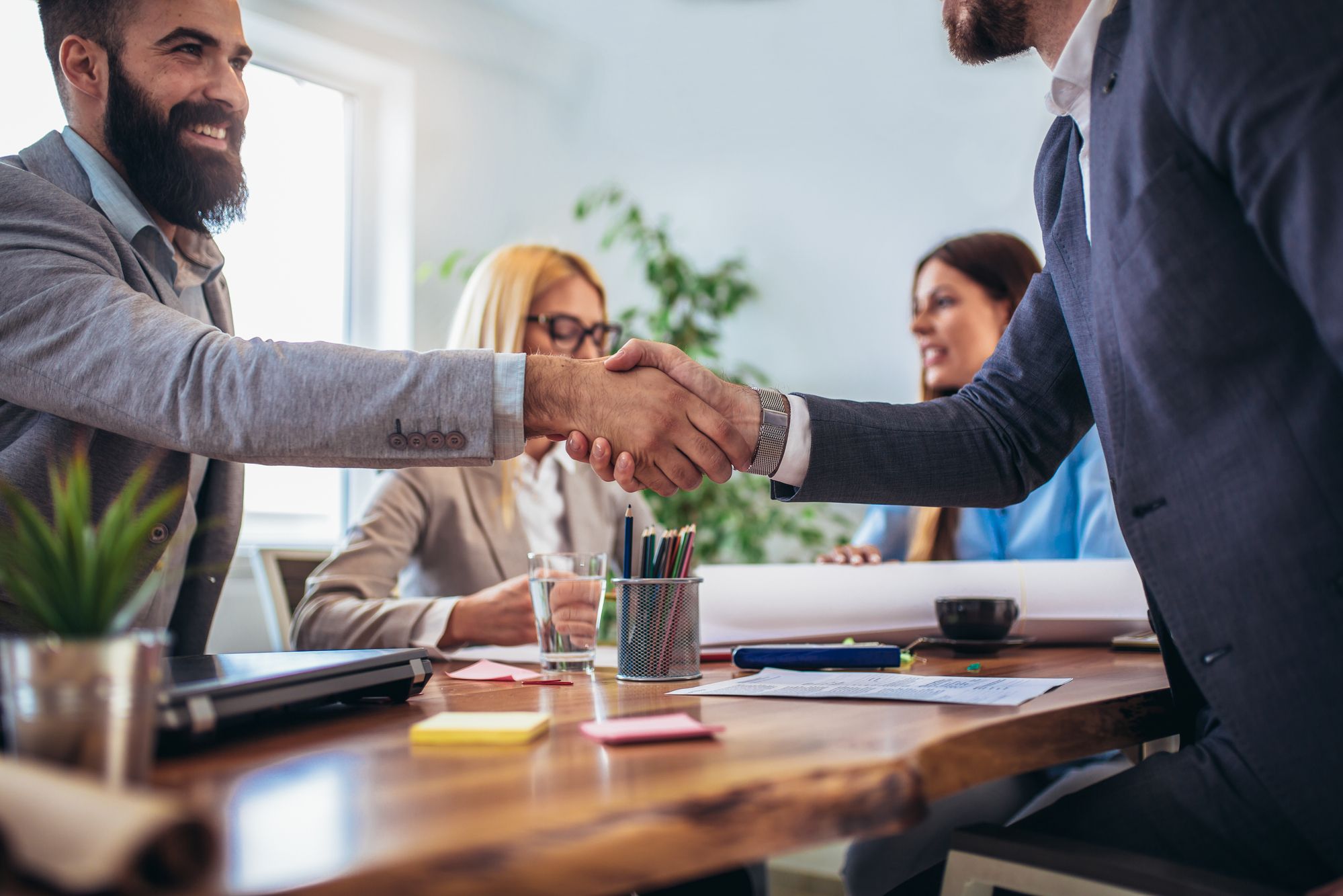 people shaking hands above a conference table