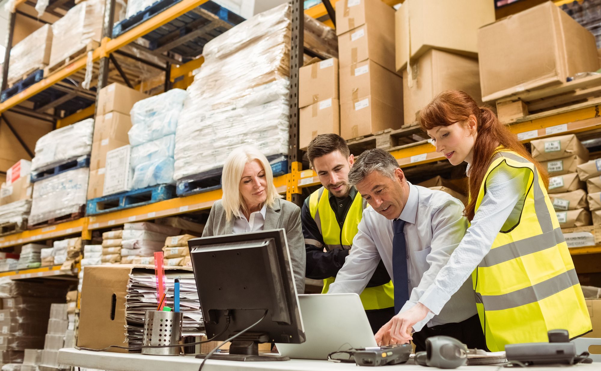 Coworkers around a computer in a warehouse